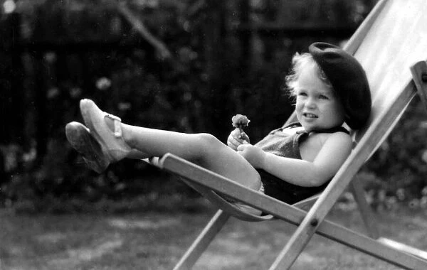 Young girl wearing a beret relaxing on a deck chair in her back garden Circa 1945