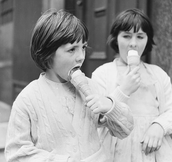 Two young girls enjoy eating ice creams 9th April 1962