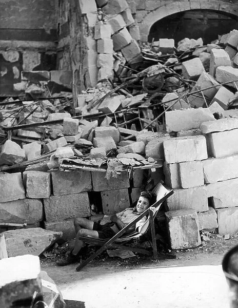 A young Maltese boy making himself as comfortable as possible by the ruins of his home