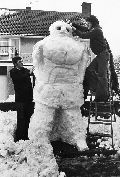 Two young men build a giant snowman, Wales, 22nd February 1978