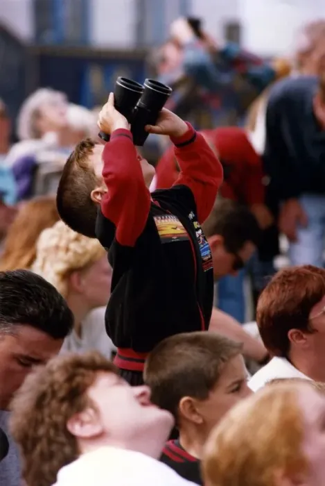 Framed Print : A young spectator looks through a pair of binoculars at an air display at the Sunderland