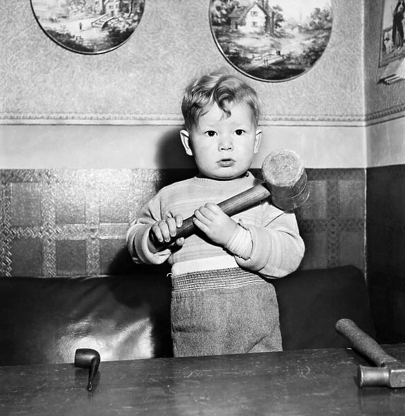 Young toddler boy holding a heavy hammer December 1952 C6391-004