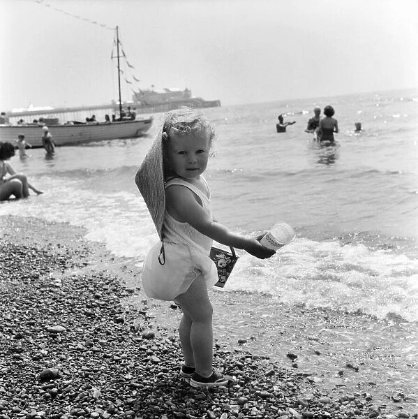 Young toddler on Brighton Beach goes for a paddle in the sea during the hot summer