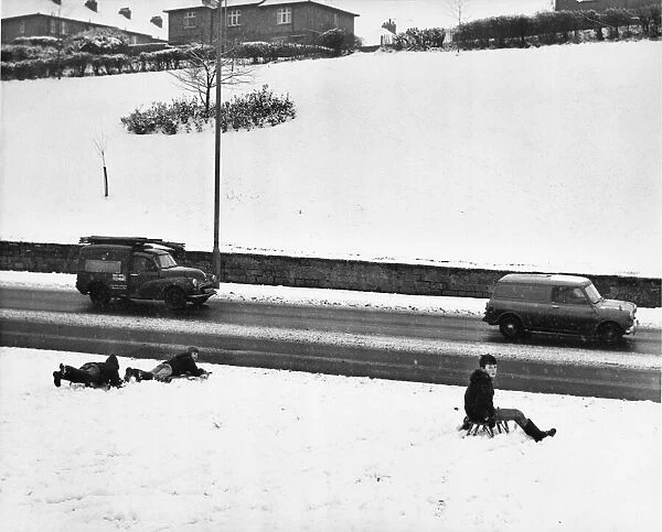 Youngsters sledge down the snow covered bank stopping only feet off the busy Newcastle