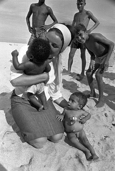 Youth worker cuddling babies on the beach in Brazil beaches baby with a