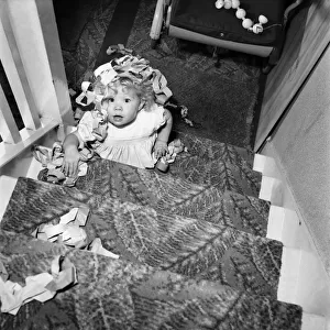 15 month-old Janice Cook with Christmas chains climbing the stairs November 1953