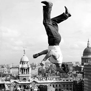 Acrobat Frank Paulo jumps upside down on a trampoline on the roof of the GPO building in