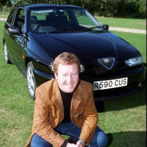 Actor Jonathan Watson September 1997 after testing ALFA ROMEO 145 kneeling in front of