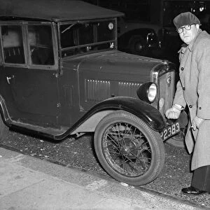 Actor Peter Sellers seen here trying to start his Austin 7 motor car outside the Paris