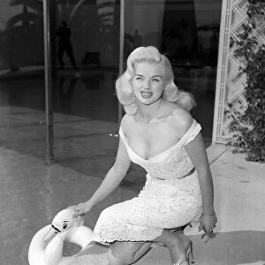 Actress Diana Dors with an inflatable swan as she poses by a swimming pool at cannes film