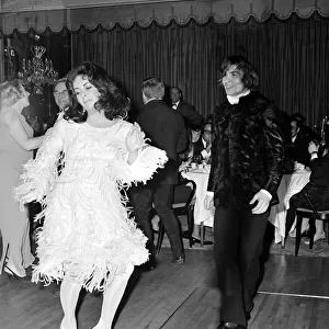 Actress Elizabeth Taylor dancing with Nureyev wearing an unusual feathered dress