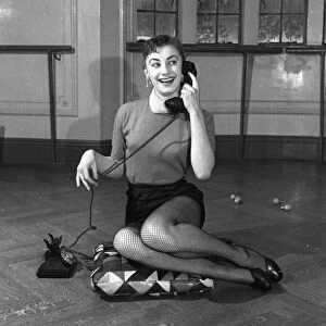 Actress Jean Marsh aged 17 posing sitting ona cushion and holding a phone