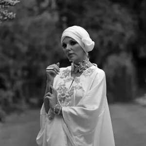 Actress Joan Collins modelling outfits that she will wear on a trip to Tokyo to judge a