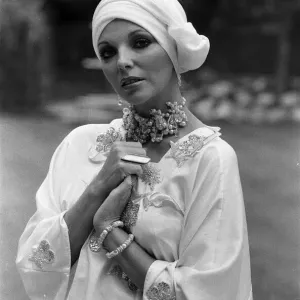 Actress Joan Collins modelling outfits that she will wear on a trip to Tokyo to judge a