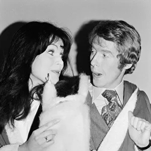 Actress Madeline Smith poses with Michael Crawford dressed in Father Christmas attire at