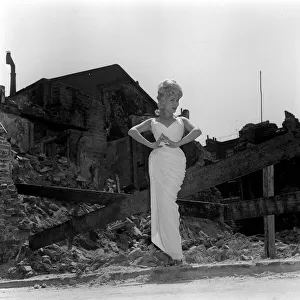 Actress and singer Jill Day June 1962 posing outside a demolished building