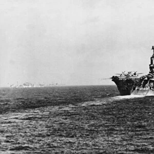 The aircraft carrier HMS Ark Royal supply convoy in the background making its way to