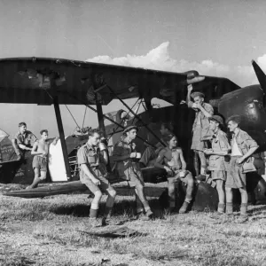 Print of RAF bomb disposal squad resting on an Italian biplane Print of RAF bomb disposal squad resting on an Italian biplane