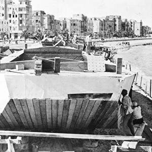 Alexandria, Egypt. Canvas being nailed onto the sides of a flat bottomed barge called a