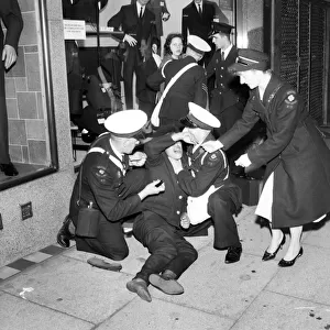 Ambulance men and medical workers attend to a Beatles fan who was injured in a crush as