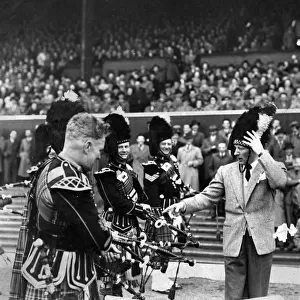 American actor and comedian Danny Kaye, complete with busby puts the Pipe band through