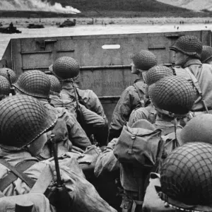 American assault troops in landing craft huddle behind the protective front of the craft