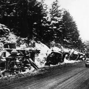 American and German military vehicles lie overturned on the roadside after being put out