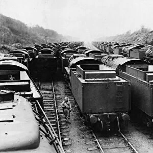 An American soldier stands on guard, surrounded American built locomotives at a rail