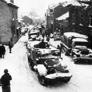 American tanks and infantrymen on their way up to the front pass through the street of