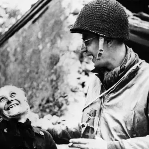 An American troop shares a joke with a civilian while on duty. 22nd June 1944 An American troop shares a joke with a civilian while on duty. 22nd June 1944