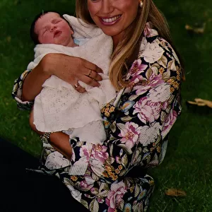 Anneka Rice holding baby smiling sitting on grass wearing flowery print shirt TV