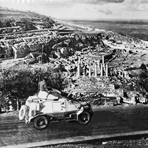Armoured cars of the South African Field Force pass ancient ruins in Cyrene during Second