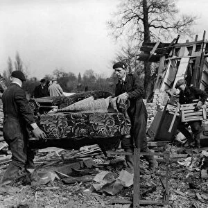 ARP rescue workers removing settee from blitzed army huts used as dwellings in a field in