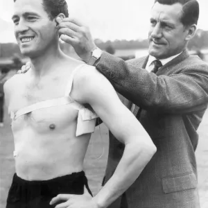 Arsenal manager George Swindin attaches a receiver to left back Jimmy Bloomfield to try Arsenal manager George Swindin attaches a receiver to left back Jimmy Bloomfield to try