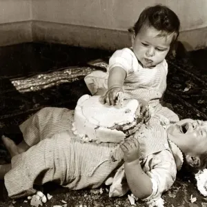 Two babies enjoying their birthday cake. Circa 1950 NO USE FOR GREETINGS Two babies enjoying their birthday cake. Circa 1950 NO USE FOR GREETINGS