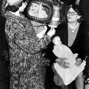 A baby in a gas mask smiles at her mother. 25th August 1939 A baby in a gas mask smiles at her mother. 25th August 1939