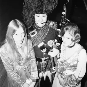 Two ball goers pose with the piper at the Birmingham and West Midlands Scottish Society