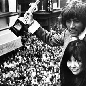 Barry Gibb of the Bee Gees holding the John Stephen statuette presented to him by Miss