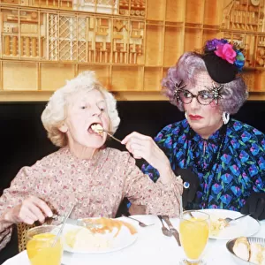 Barry Humphries as Dame Edna Everage glasses hat with Madge open mouth eating in La