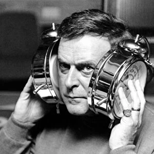 BBC radio disc jockey Terry Wogan pictured with large alarm clocks to his ears