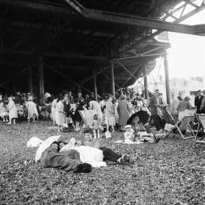 Beach scene Brighton, East Sussex. Crowds seek cover from a summer shower under the pier