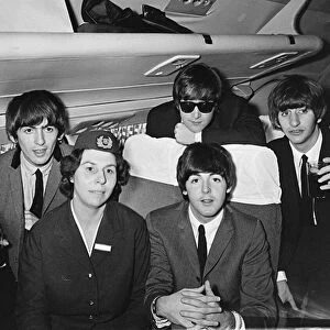 The Beatles with an air hostess on a plane flying into Speke airport, Liverpool