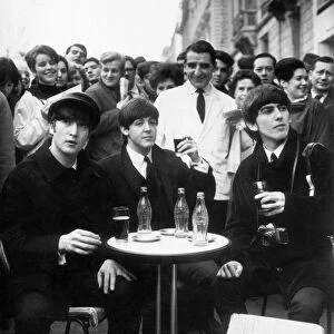 Three Beatles - John, Paul and George enjoy a glass of coca cola at a street cafe in