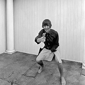 Beatles at pool in a private home in Los Angeles. Ringo Starr playing cowboy at Beatles