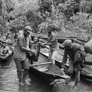 Biafran soldiers and helpers seen here carrying an injured comrade onto a canoe to cross Biafran soldiers and helpers seen here carrying an injured comrade onto a canoe to cross