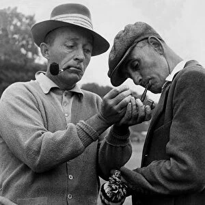 Bing Crosby and caddie break for a smoke during a round of golf, September 1952