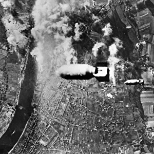Two bombs drop from a US heavy bomber towards U-boat yards in the German district of