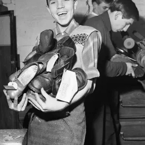 A boy carries a bundle of shoes. He is at work A boy carries a bundle of shoes. He is at work