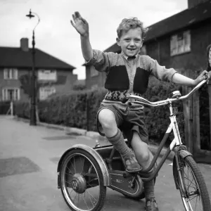 Un garçon joue sur son tricycle dans un immeuble de rapport municipal tandis que sa mère regarde 1955.