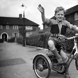 A boy plays on his tricycle on a council estate as his mother looks on 1955